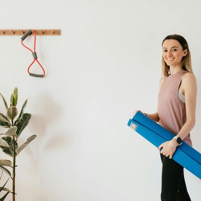 A yoga mat rolled up next to a small plant.